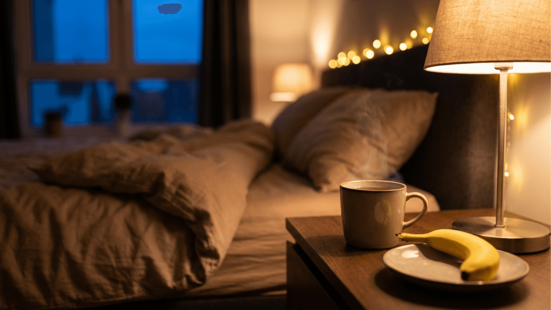 Eine reife Banane und eine Tasse Tee auf einem Nachttisch im gemütlichen Schlafzimmer, symbolisch für Banane vor dem Schlafen.