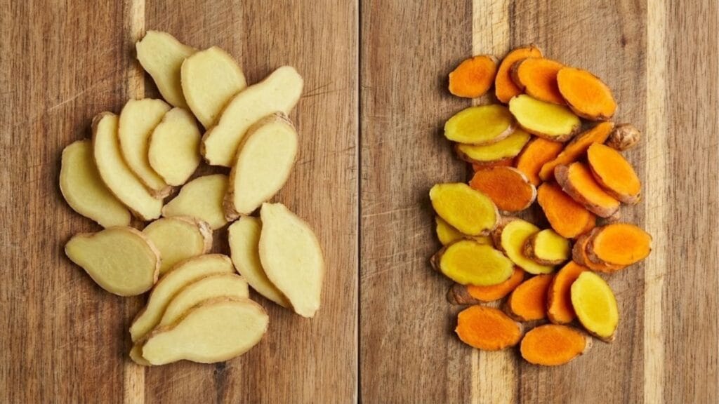 Frischer Ingwer und Kurkuma im Vergleich auf einem Holzbrett.