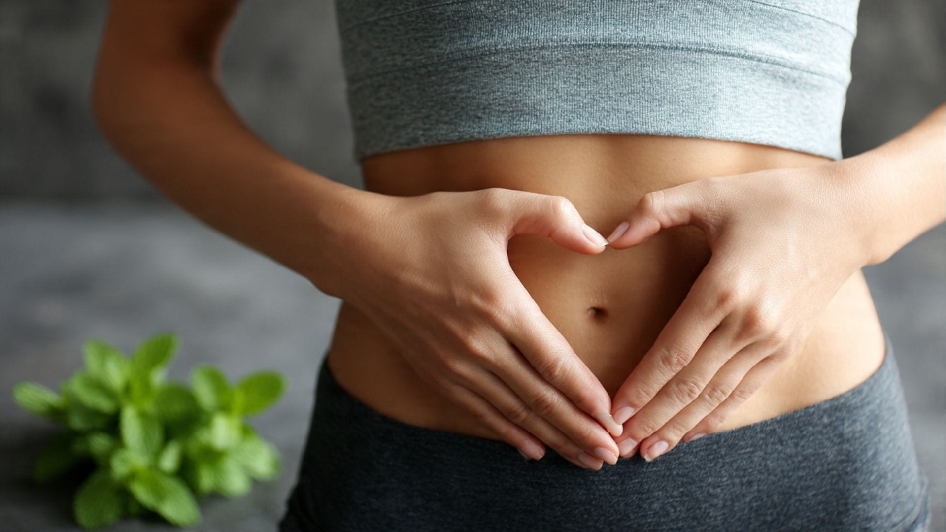 Frau formt ein Herz auf ihrem flachen Bauch: Wirkung von Pfefferminztee gegen Blähbauch